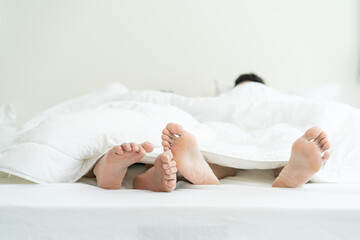 Close up feet of male gay couple lying down on bed, cover with blanket