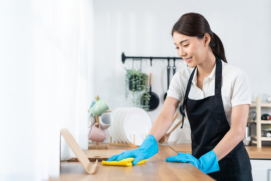 Asian young cleaning service woman worker clean kitchen table at home. 