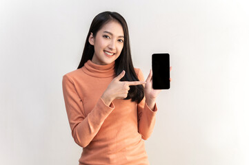 Portrait photo of young beautiful Asian woman pointing at black empty space on smart phone background can use for advertising or product presenting concept. Asian woman pointing at empty smart phone .