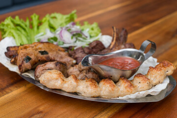 Assorted delicious grilled meat with lettuce and onion. Mixed grilled bbq meat with tomato sauce.Lamb, chicken. Top view, close up with copy space.