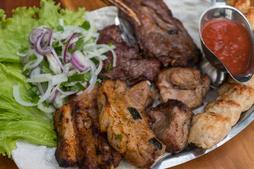 Assorted delicious grilled meat with lettuce and onion. Mixed grilled bbq meat with tomato sauce.Lamb, chicken. Top view, close up with copy space.