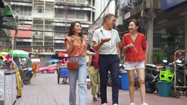 Group of Asian people friends tourist walking and shopping together at Chinatown in Bangkok city, Thailand. Male and female friend enjoy and having fun outdoor lifestyle travel and eating street food.