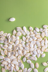 A composition of healthy pumpkin seeds in a shell on a green background for a healthy diet.