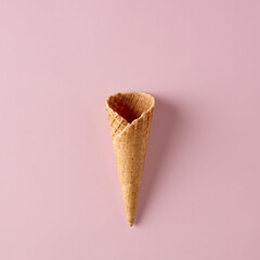 Empty wafer ice cream cone on pink background.