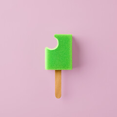 Popsicle ice cream made out of sponge with bite mark on pastel pink background. Minimalistic...