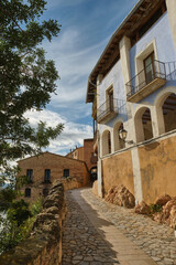 Miravet, stone cobblestone street and a nice blue house with balconies in the old town of Miravet, Tarragona, Spain