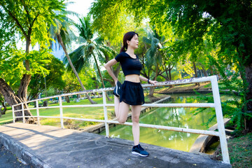 Asian woman waring a black dress warm up before jogging in the park