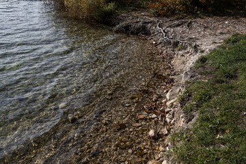 Small lake, pond coastal line with small vawes.