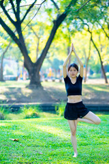 Asian woman wearing a black dress play yoga in the park