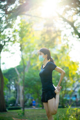 Asian woman waring a black dress wearing medical mask warm up before jogging in the park