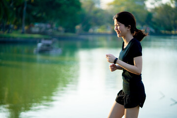 Asian woman wearing a black dress  jogging in the park near river in the city