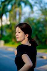 Asian woman wearing a black dress  jogging in the park near river in the city