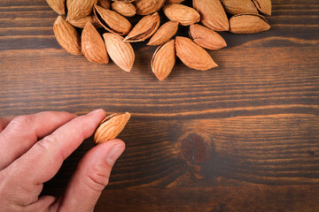 Almonds in a man 's hand. Dark wood texture background