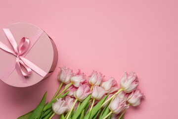 Fresh pink tulips and round gift box on pastel pink background. 8 march international day or Mother's day background, top view, copy space