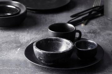 Black ceramic set with bowl abd plate on cocnrete background.