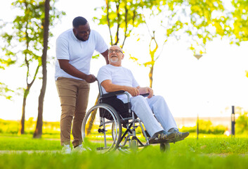 Caregiver and old man in a wheelchair. Professional nurse and patient walking outdoor in the park at sunset. Assistance, rehabilitation and health care.