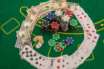multicolored poker cards chips dollar banknotes laid out on a new green poker table.
