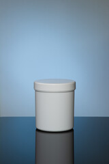 Mockup of white cosmetic jar with reflection on spot light blue background