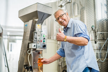 Senior man is using machine to cork wine bottle in his distillery.