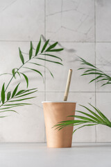 Takeaway craft paper cup on white background with green palm leaves