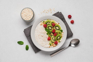 Oatmeal with kiwi and raspberries in ceramic bowl on light background with copy space. Healthy breakfast top view