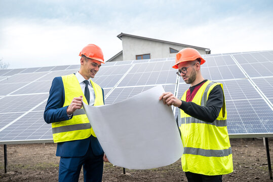 two professionals in workwear discuss solar panels and their impact.