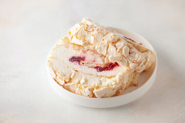 Homemade Meringue Cake Sweets Roll with Cherry jam on ceramic plate.