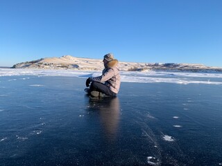 Fototapeta premium a man in winter meditates on the ice of the Volga river against the background of the hills
