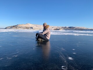 Fototapeta premium a man in winter meditates on the ice of the Volga river against the background of the hills