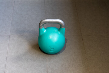 A blue kettlebell on the ground in the gym
