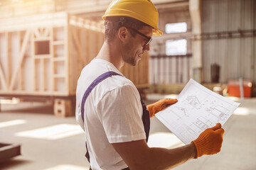 Joyful male worker studying architectural plan at construction site