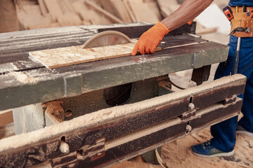 Male worker using industrial woodworking equipment in workshop
