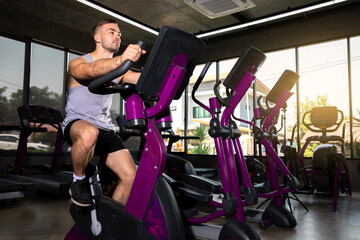 Fototapeta na wymiar Attractive man working out on an exercise bike in gym. healthy concept