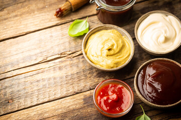 Classic set of sauces, American yellow mustard, ketchup, barbecue sauce, mayonnaise on wooden...