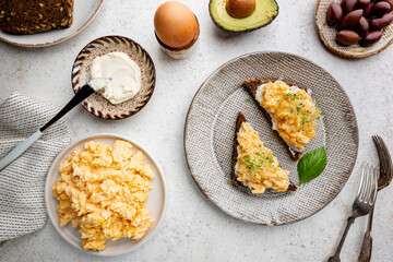 Scrambled egg sandwich with cream cheese on rye toast for breakfast on white background, top view....