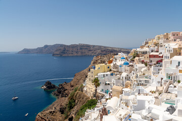 Fototapeta na wymiar Oia, Greece - July 28, 2021: View of the town and the boat at the coastline