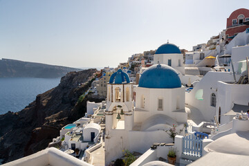 Oia, Greece - July 30, 2021: St. Anastasi and St. Spirydon and the Aegean sea in the background