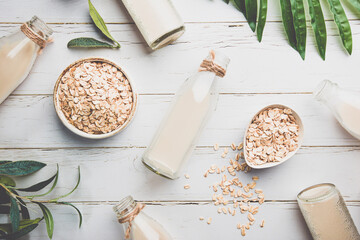 Vegan non dairy oatmeal milk in bottles on white wooden background. Lactose free milk substitute....