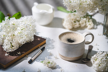 Spring composition with cup of coffee, old book and white lilac beautiful bouquet. Concept of...