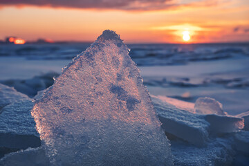 Sunset over frozen sea in winter, ice floe in orange sun light