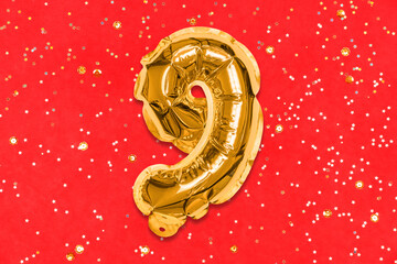 The number of the balloon made of golden foil, the number nine on a red background with sequins....