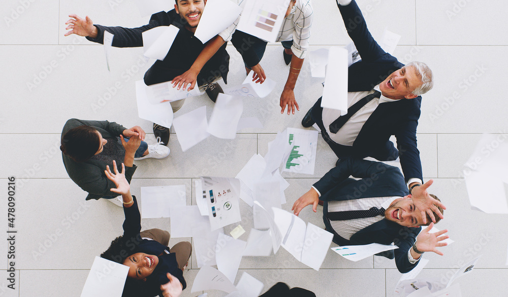 Poster Aerial shot of a diverse group of businesspeople throwing paperwork in the air in celebration while in the office