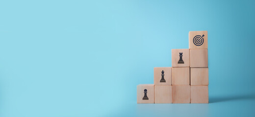 Business goals and strategies concept.  Change and strategy management for business adaptation and growth. The top of wooden cubes with "GOAL" icon standing with other "STRATEGIES" on blue background.