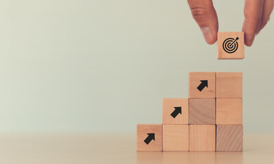 Business goal achievement concept.  Hand puts the wooden cubes with 