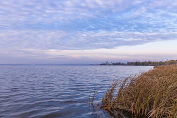 Fototapeta premium Colorful sunrise on the shores of Lake Nero. Autumn landscape with a lake in the early morning overlooking the monastery. A bright streak of light on the horizon, dawn.