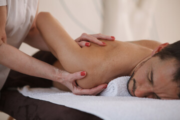 Fototapeta na wymiar Cropped shot of a man getting professional shoulder massage at spa salon