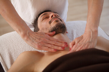 Mature man enjoying relaxing massage at spa, smiling with his eyes shut