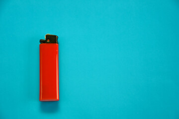 Gas lighter of red color on a blue background. Close-up surface for your design. Empty gas plastic lighter mockup element. Close-up shot, top view.