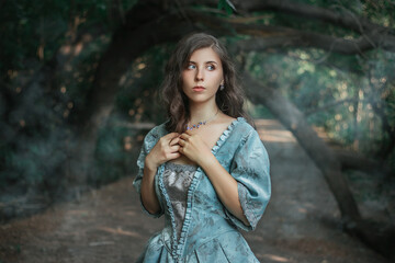 Beautiful young woman in 18-19 century dress and white gloves in the forest by the pond. Girl in a mysterious forest. The photo