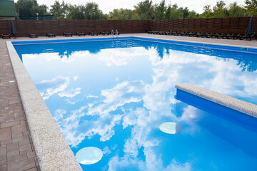 Swimming pool with water reflecting sky and clouds